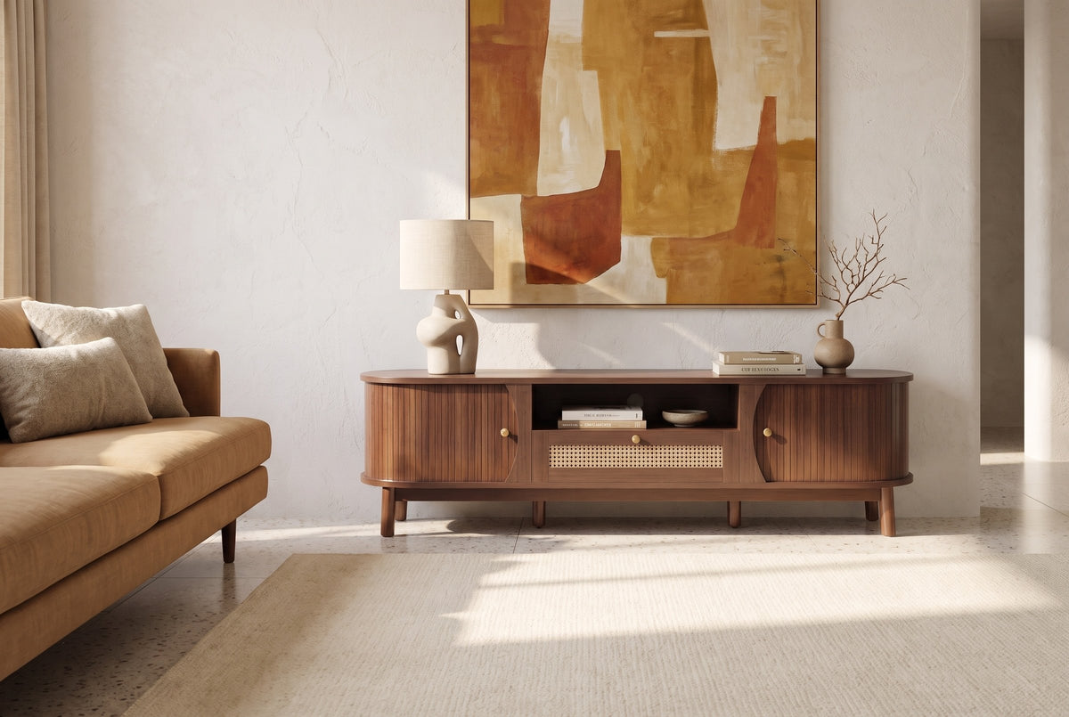 The Livia media console in Natural Walnut below a large ochre and rust painting, in a bright desert-modern den with plaster walls, a terrazzo floor and a camel sofa