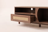 Close-up of the Livia console's centre: the hand-woven rattan drawer pulled out below the open shelf