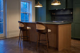 Two Locorotondo counter stools at a fluted-oak kitchen island with a dark stone counter