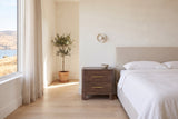 Lodi nightstand in Brown Oak beside a bed with white linen in a bright Kelowna lake-house bedroom