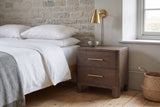 Lodi nightstand in Brown Oak against a limestone wall in a Quebec City bedroom with white linen