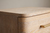 Close-up of the Lodi top corner: the rounded top slab, the drawer front curving round the corner and a brushed-gold pull