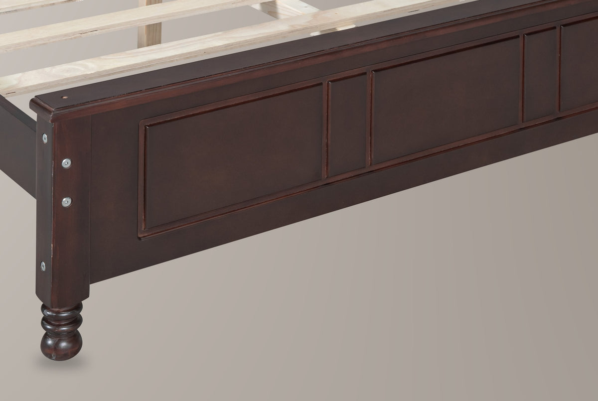 Close-up of the walnut Loreto footboard corner: square post with round bolt heads and a turned bun foot