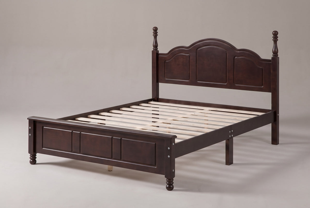 Loreto turned-post bed in walnut, three-quarter view of the bare frame on a warm grey studio backdrop