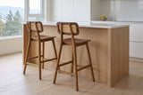 Two Lovere counter stools at a white-oak island with a white quartz counter in a bright Vancouver kitchen, seen from behind