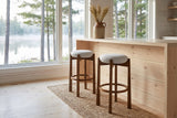 Two Lucera bar stools on a jute runner at a pale pine counter by a lake window in a Muskoka cottage