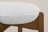 Close-up of the thin round linen-look cushion sitting in the notched top of a Dark Walnut rubberwood leg