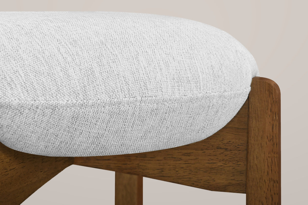 Close-up of the thin round linen-look cushion sitting in the notched top of a Dark Walnut rubberwood leg