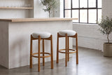 Two Lucera bar stools in Walnut at a limewashed plaster bar counter in a white-brick Montreal loft with a black steel window