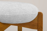 Close-up of the thin round linen-look cushion sitting in the notched top of a Walnut rubberwood leg