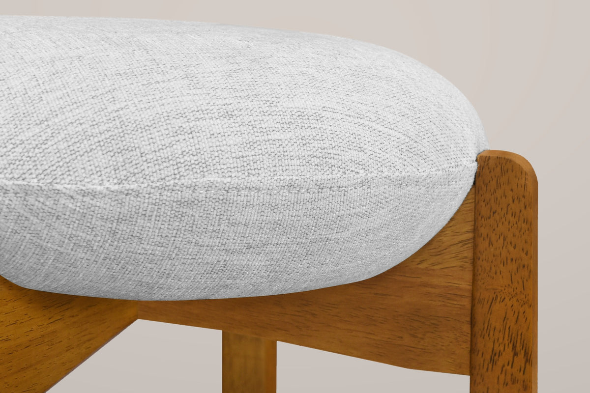 Close-up of the thin round linen-look cushion sitting in the notched top of a Walnut rubberwood leg