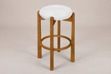 Lucera backless bar stool in Walnut, three-quarter view on a warm light-grey studio backdrop