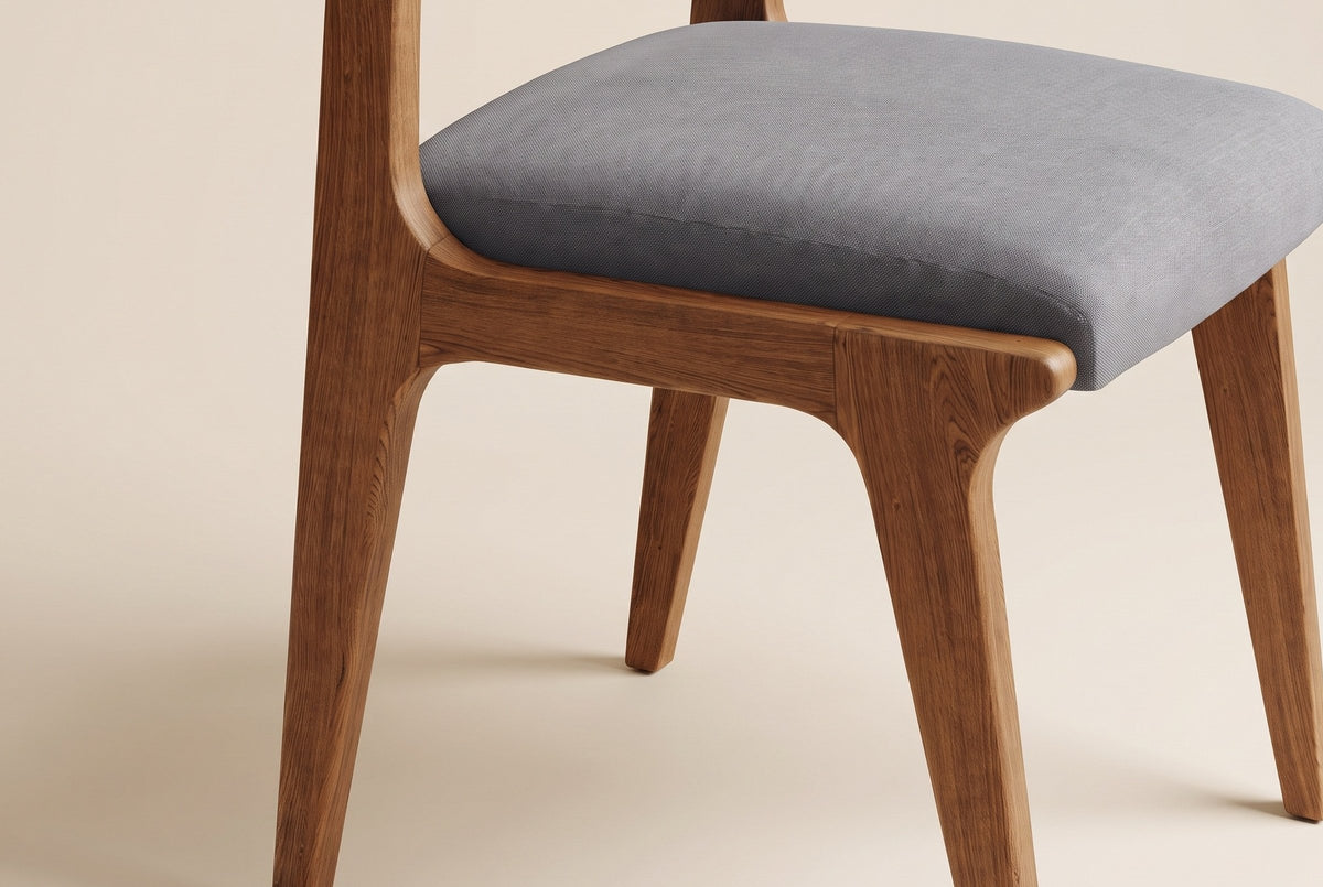 Close-up of a Lucrezia dining chair in the Walnut finish: grey fabric seat cushion inset in the oak seat frame and tapered legs, on an off-white background