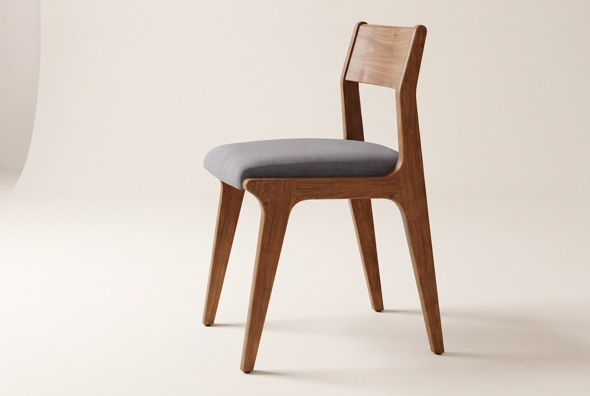 Lucrezia dining chair in the Walnut finish with a grey fabric seat, side three-quarter view on an off-white background