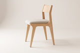 Lucrezia dining chair in the White Oak finish with an off-white fabric seat, side three-quarter view on an off-white background