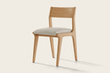Lucrezia dining chair in the White Oak finish with an off-white fabric seat, front three-quarter view on an off-white background