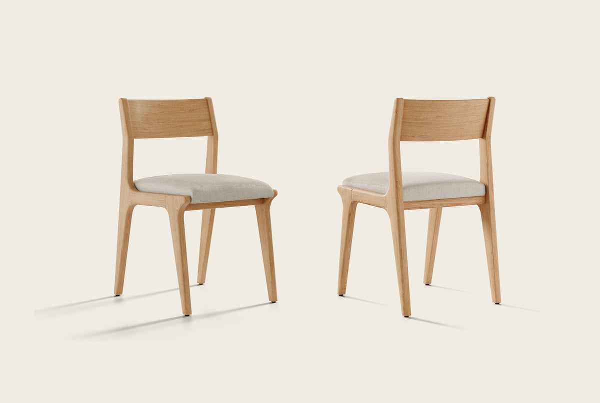 Two Lucrezia dining chairs in the White Oak finish with off-white fabric seats, one seen from the front and one from the back, on an off-white background