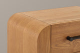 Close-up of the rounded waterfall corner in the brown wood finish, the seam to the flat top and the end of a black bar handle