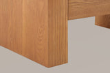 Close-up of a brown slab leg standing square on the floor below the bottom drawer, with the far leg behind