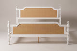 Manarola cane panel bed in antique white, straight front view from the foot on a studio backdrop