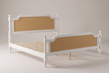 Manarola cane panel bed in antique white, three-quarter view on a warm light-grey studio backdrop