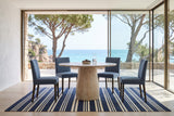 Marano round dining table in a Begur villa above the sea, with white lime plaster, a navy striped rug
