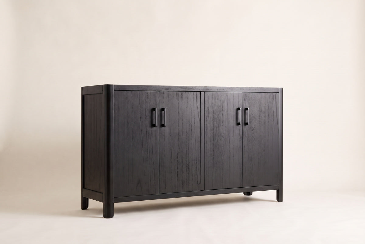 The Maren storage cabinet in Black, front three-quarter view: black-stained wood veneer doors with the grain showing, rounded corners and short legs, on an off-white studio background