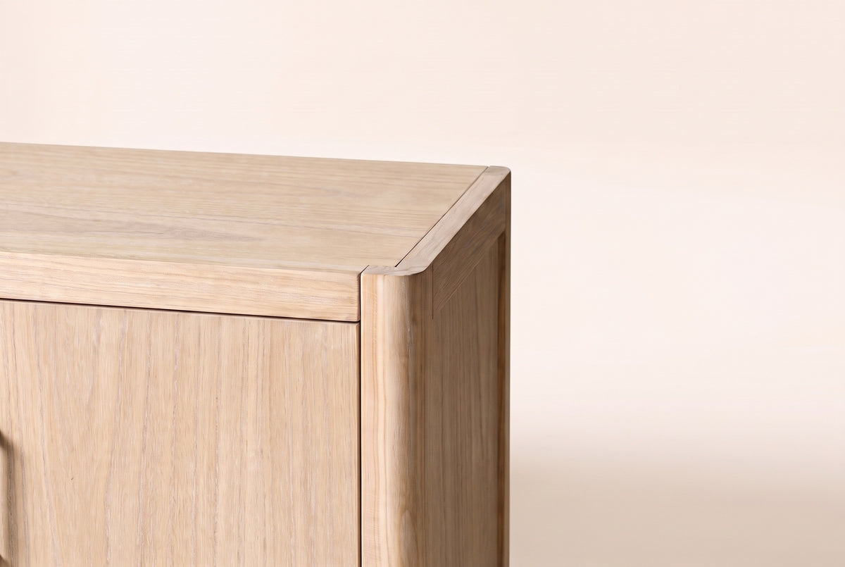 Close-up of a front top corner of the Maren cabinet in Natural: the rounded corner post and the open grain of the wood veneer