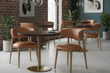Marlow Hazelnut leather dining chairs around bistro tables in a brick-walled cafe