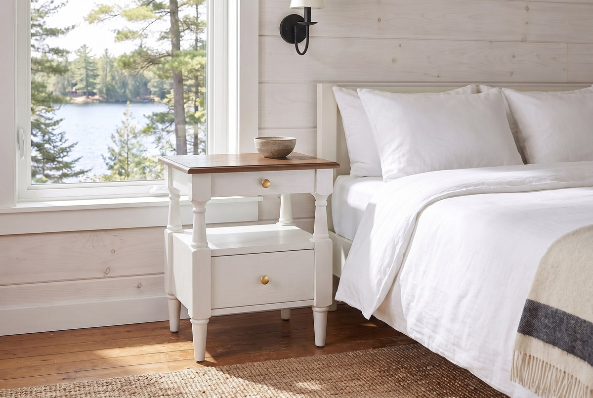 Marsala nightstand in Milk White beside a bed in a whitewashed pine Muskoka cottage bedroom with a lake view
