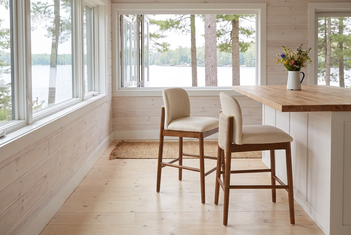 Two Menaggio counter stools pulled out from a butcher-block island in a Muskoka cottage kitchen with a window onto the lake