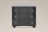 Merano nightstand in Black, straight front view: three wave-front drawers, six round brass knobs, four bun feet