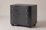 Merano 3-drawer nightstand in Black ash, three-quarter view on a warm grey studio backdrop