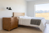 Merano nightstand in Honey Brown beside a bed in a white Calgary foothills bedroom with a view of the Rockies