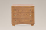 Merano nightstand in Honey Brown, straight front view: three wave-front drawers, six round brass knobs, four bun feet