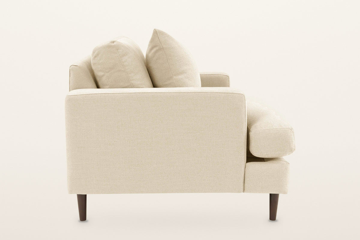 Mombaruzzo accent chair from the side on a warm white studio backdrop: the flat arm panel