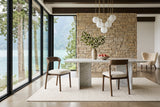 Two Mondavio dining chairs at a white marble slab-leg table in a Harrison Lake house, with a sandstone wall