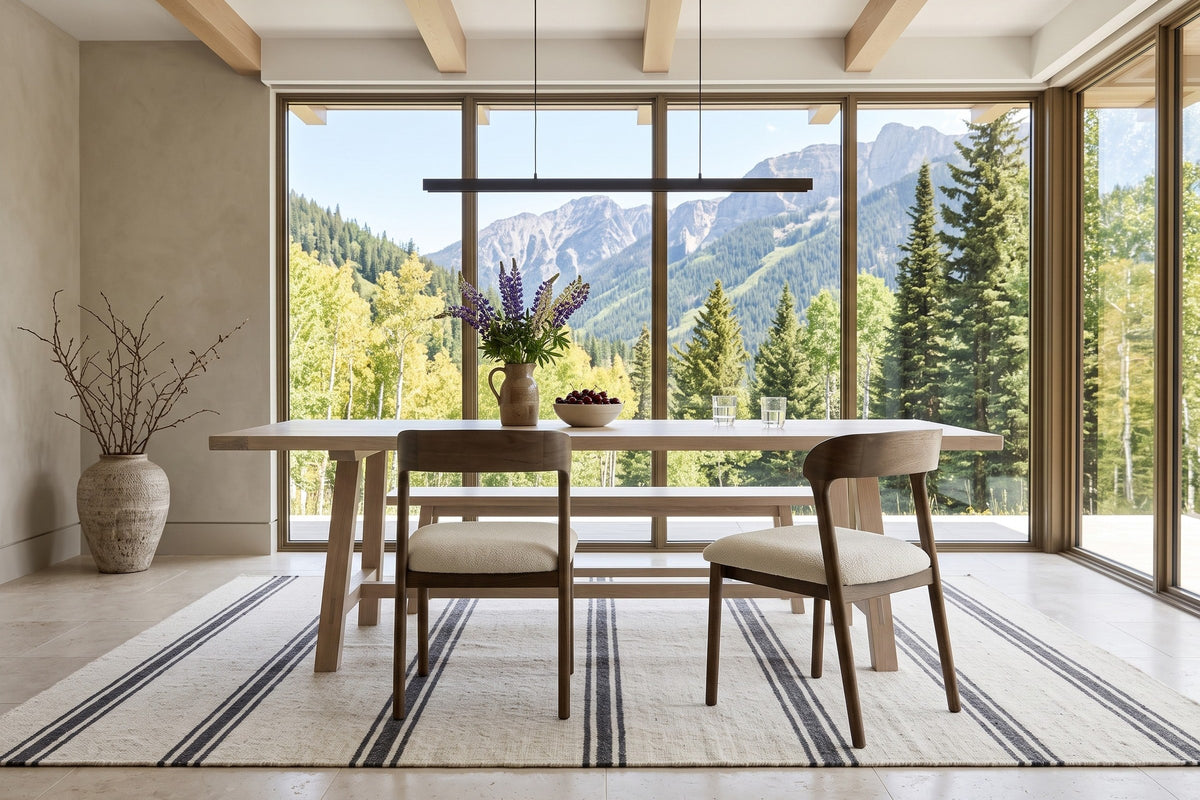 Two Mondavio dining chairs seen from behind at a white-oak trestle table in a Panorama mountain house