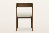 Mondavio dining chair from behind on a warm white studio backdrop: the plain outside face of the back band and the seat apron