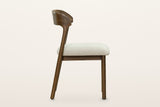 Mondavio dining chair, side view on a warm white studio backdrop: the rear legs rake back and run up into the curved back ban