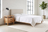 Montagnana nightstand beside a bed with white linen against a white brick wall in a bright Montreal loft