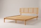 Montalcino cane platform bed in natural solid wood, three-quarter view on a warm grey studio backdrop