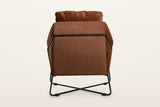 Back of the Montelupone accent chair in Rust on a warm white studio backdrop: the black rod frames the outside back