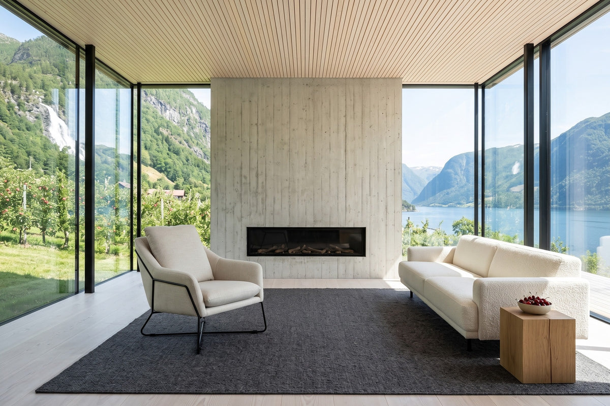 Montelupone accent chair in Taupe beside a board-formed concrete wall with a linear fireplace in a Hardanger fjord house