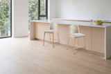 Two Monteriggioni counter stools pulled out in front of a white-oak kitchen island with a quartz top in a bright Vancouver ap