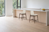 Two walnut-finish Monteriggioni counter stools pulled out in front of a white-oak kitchen island with a quartz top in a brigh