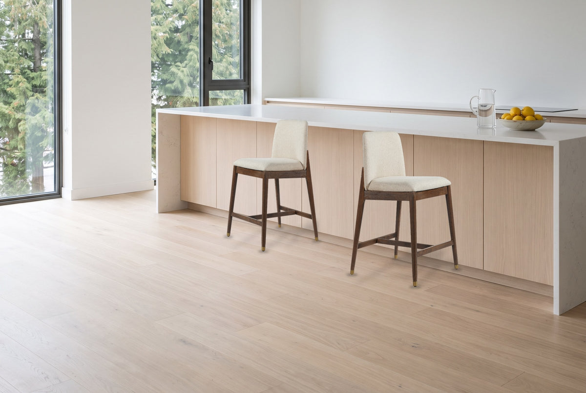 Two walnut-finish Monteriggioni counter stools pulled out in front of a white-oak kitchen island with a quartz top in a brigh