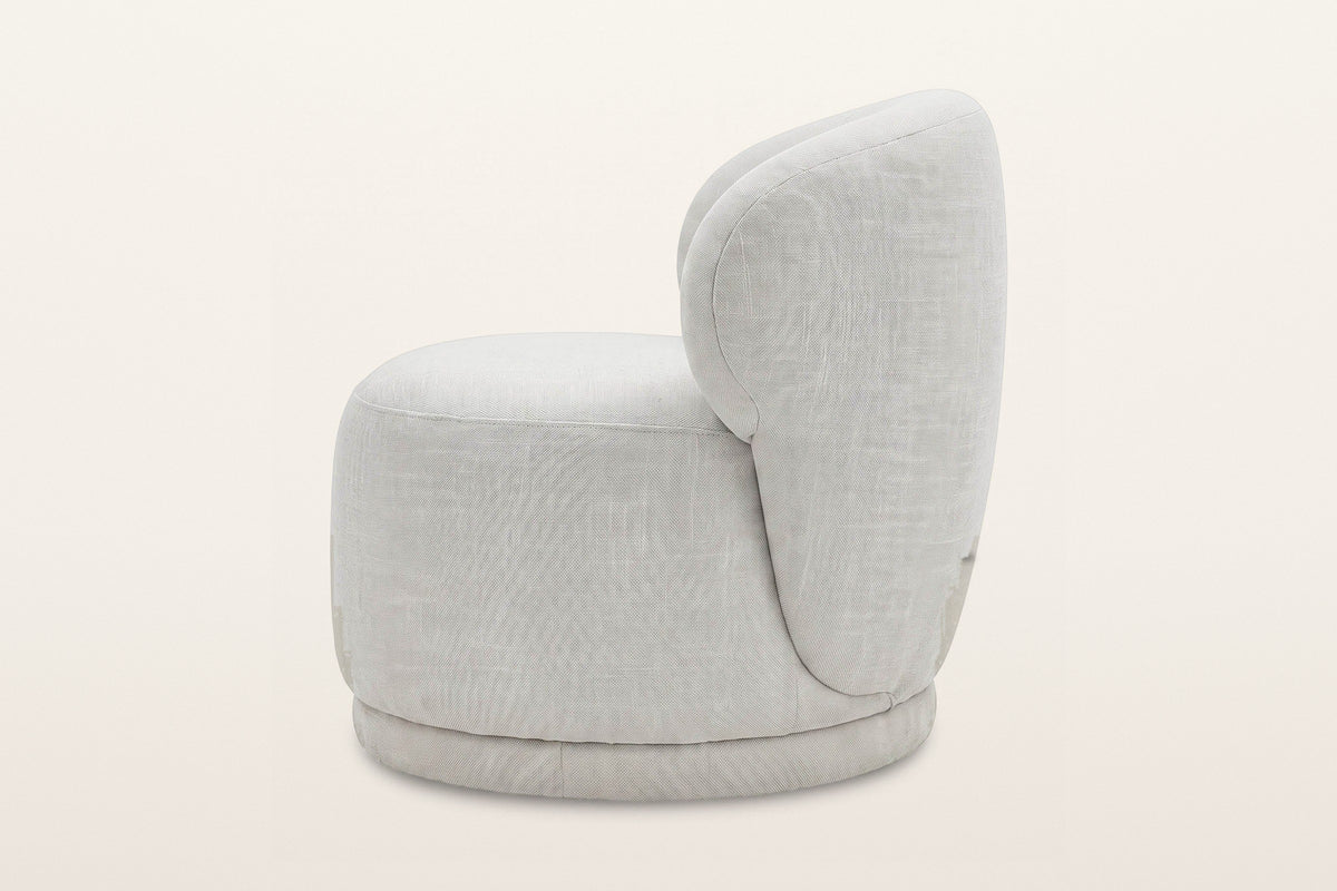 Monterubbiano accent chair in Ivory twill, side view on a warm white studio backdrop: the back wraps round and runs down