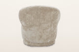 Back of the Monterubbiano accent chair in Natural velvet on a warm white studio backdrop: one smooth curved shell with a cent