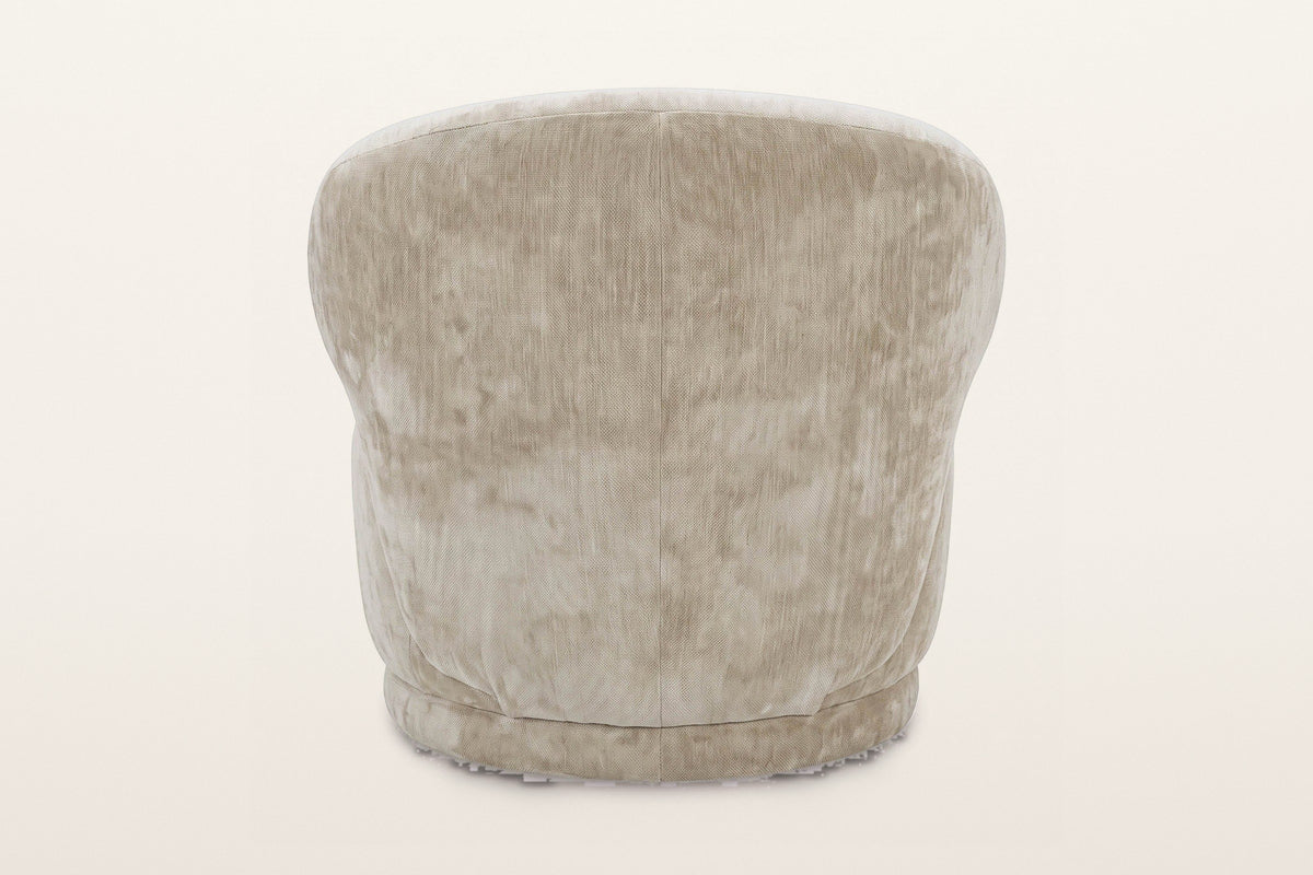 Back of the Monterubbiano accent chair in Natural velvet on a warm white studio backdrop: one smooth curved shell with a cent